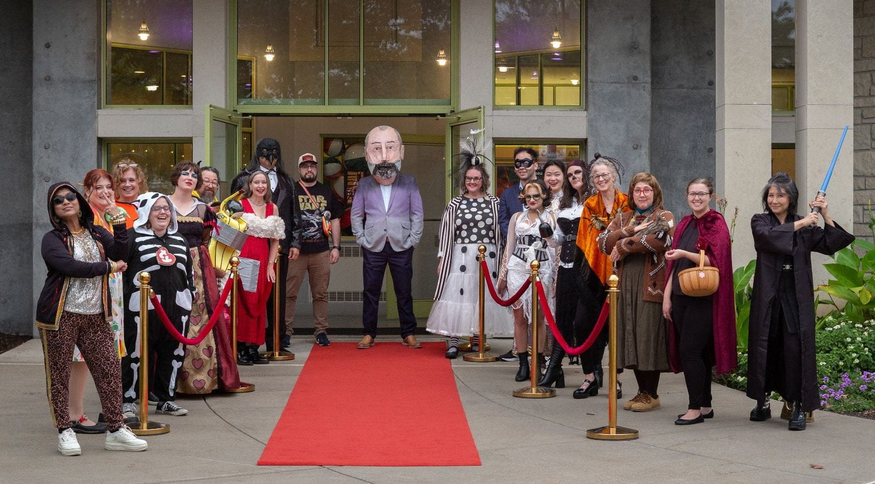 A group of people in colorful costumes standing at the entrance of the Beach Museum of Art.