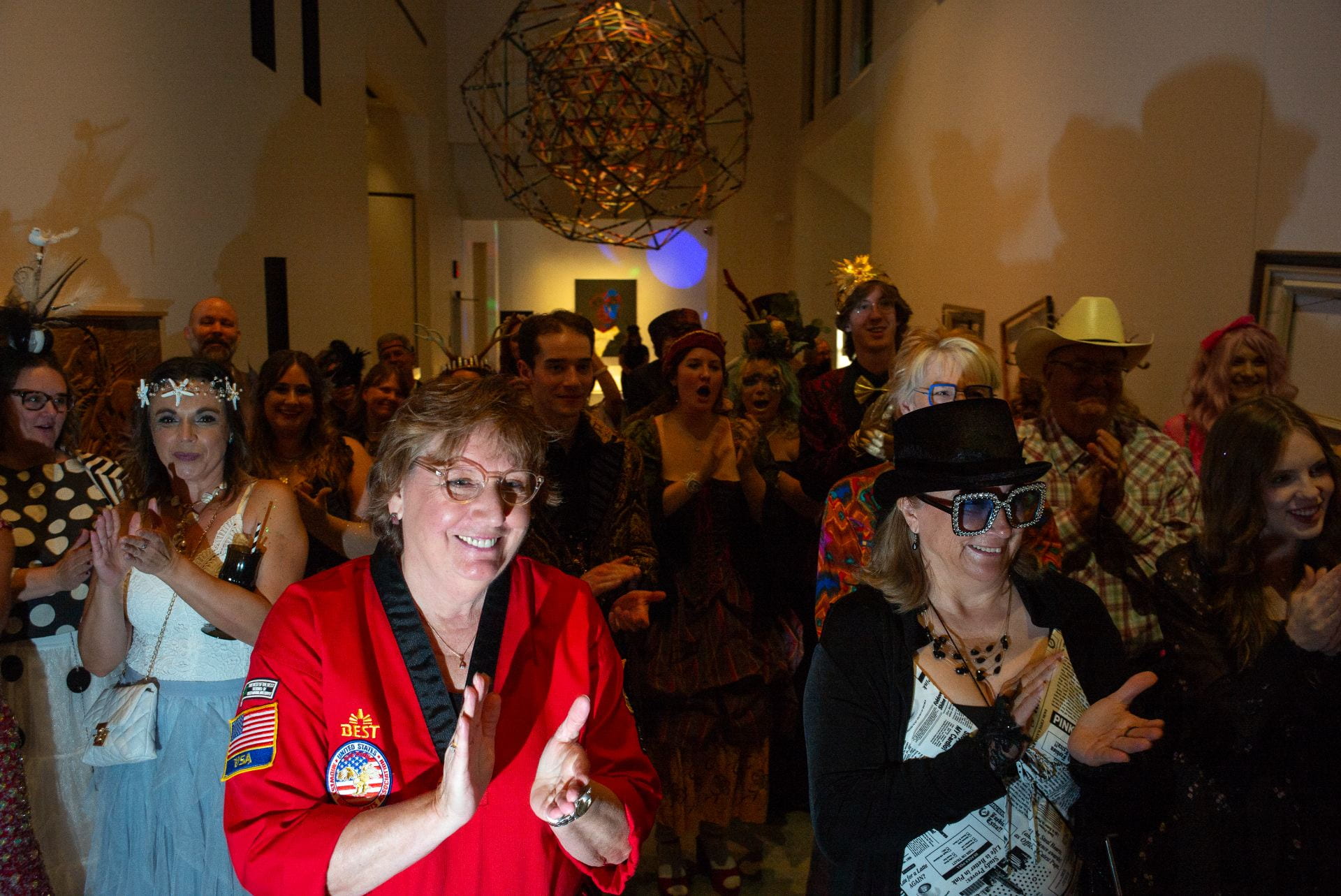 A large group of people cheering and socializing at the Beach Museum of Art.