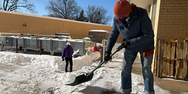 Person shovels snow from dock on university campus 