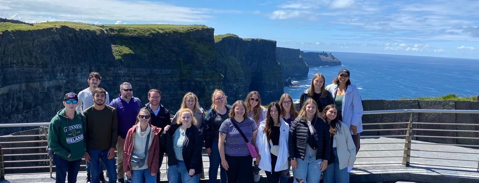 A group of students stand at a viewpoint in Ireland at the Cliffs of Moher