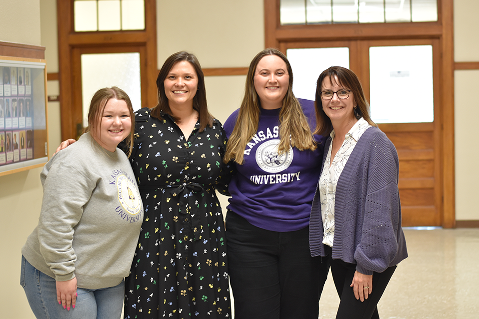 A group of women stand in a hallway and smile for a group photo