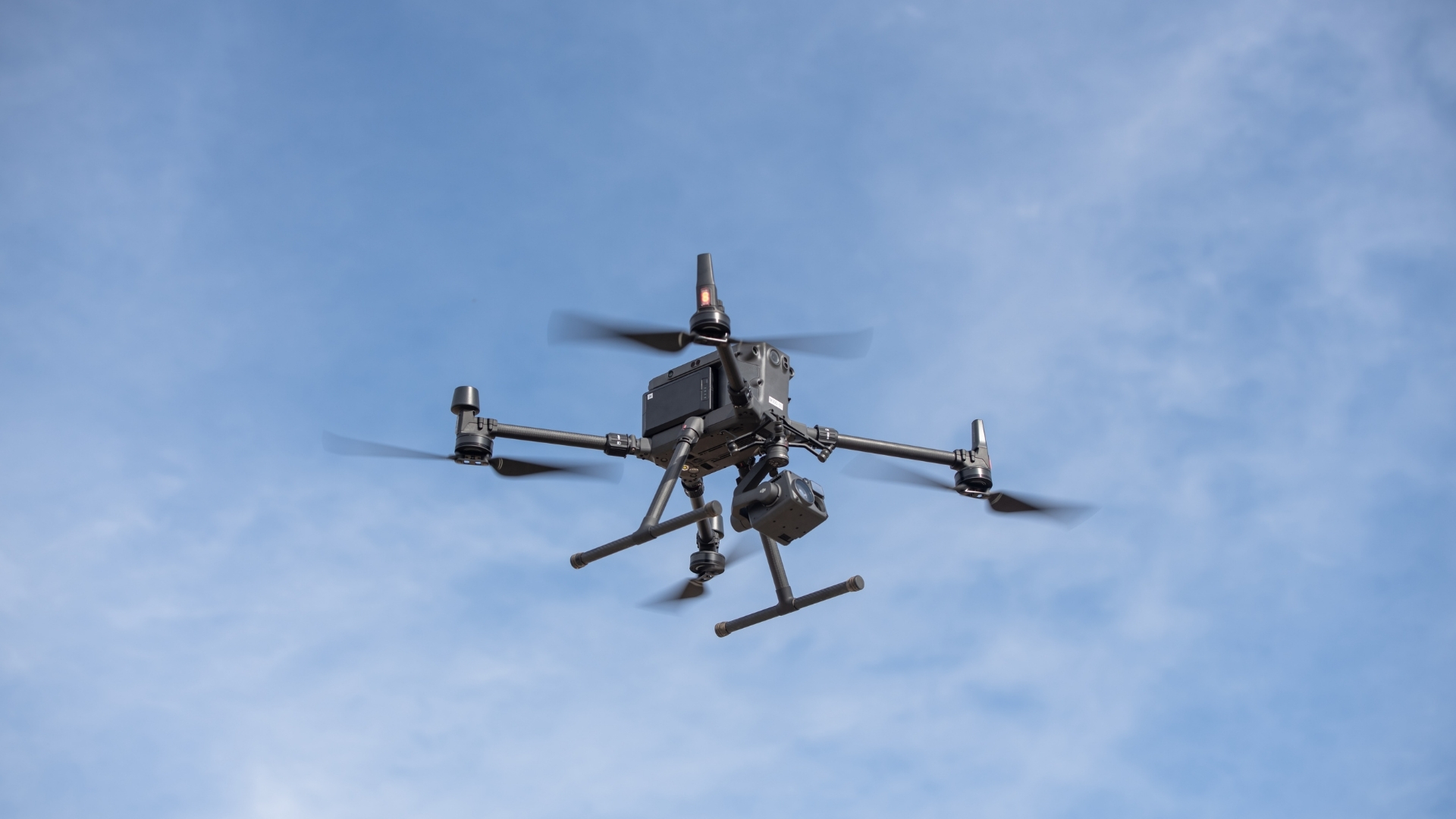 A black drone against a blue sky.