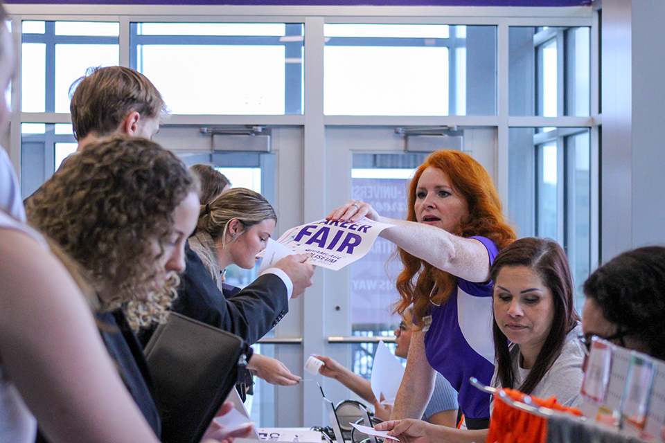 Volunteer helping check in students at the All University Career Fair.