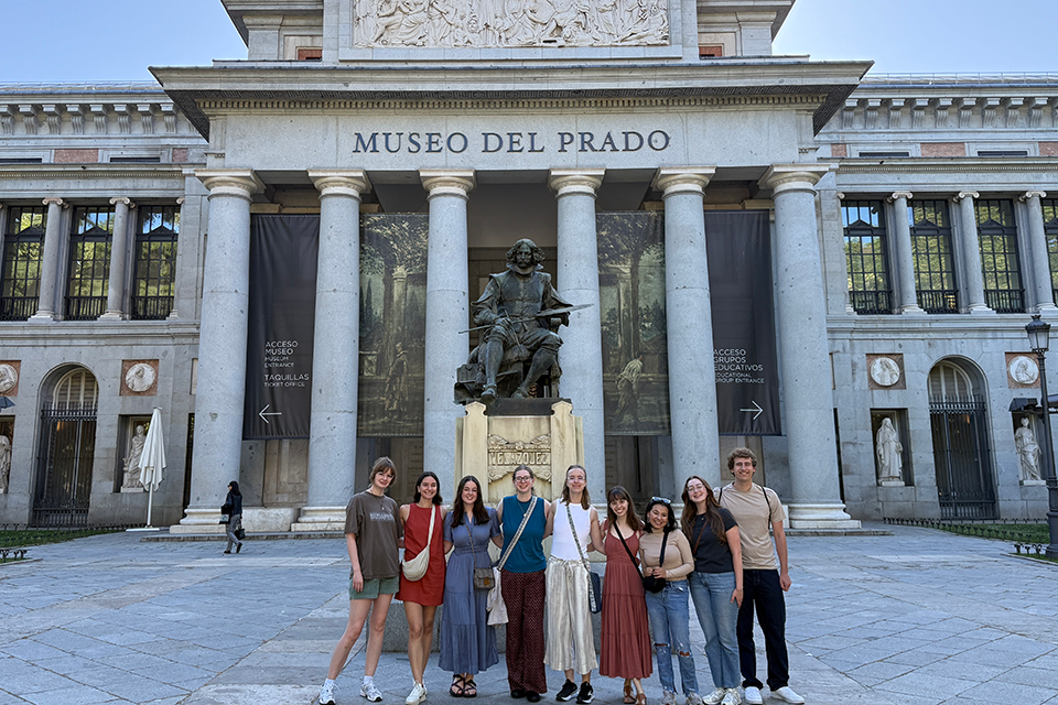 Students stand outside of a large stone building in Spain.
