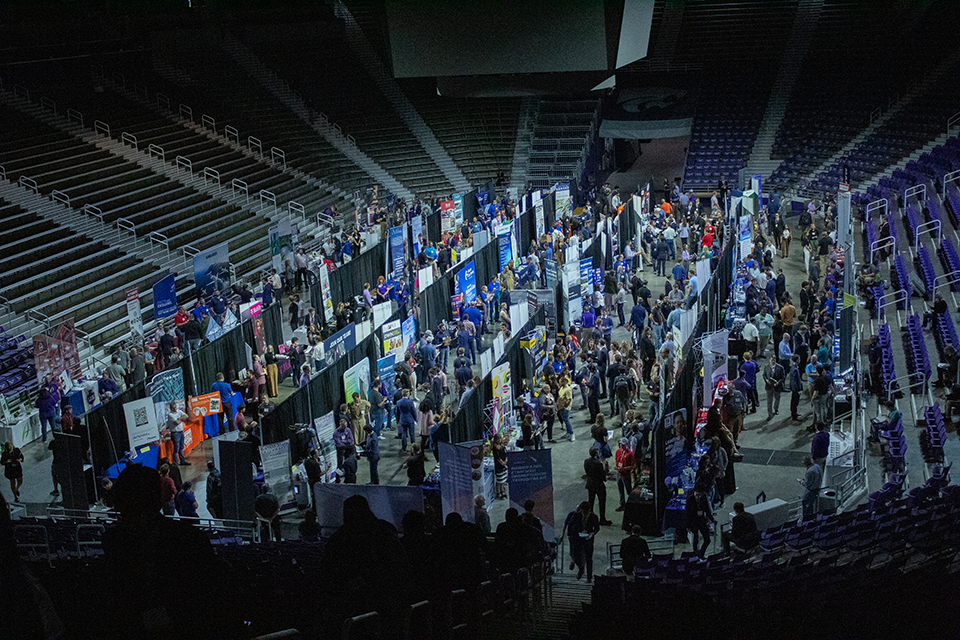 Looking down into a sports arena where students meet with employers at a career fair. 