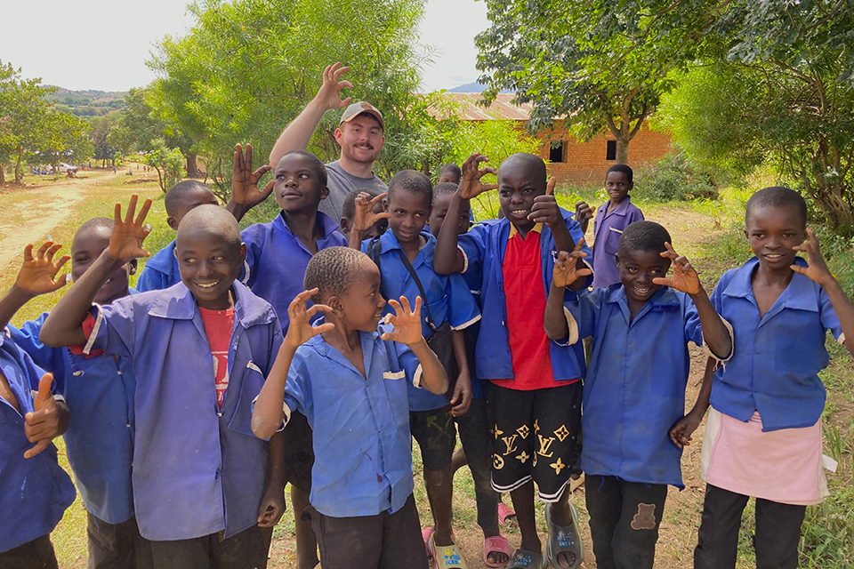 A college student from Kansas State University shows a group of Ifumbo children how to do the Wildcat hand sign.