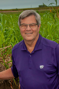 Chuck Rice wears a purple shirt and smiles for a portrait photo. 