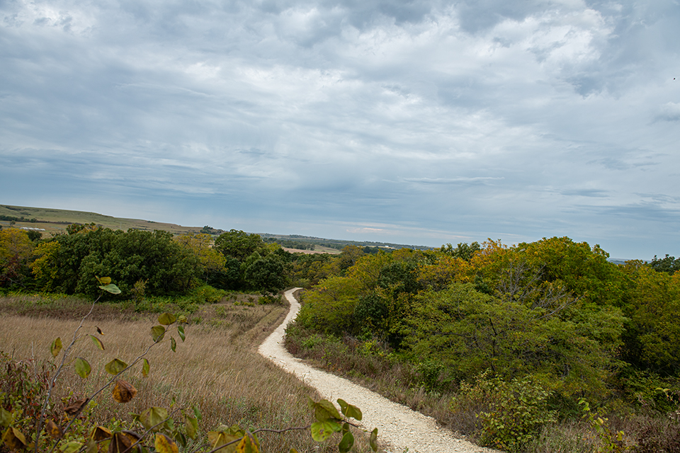 An outdoor shot shows a winding gravel path through a hilly prairie.