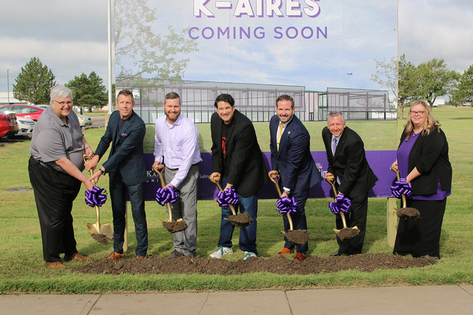 A group of university administrators line up with shovels for an outdoor groundbreaking.