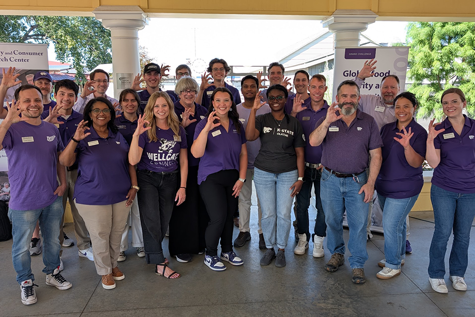 A group of Kansas State University employees pose for a group photo at the Kansas State Fair.
