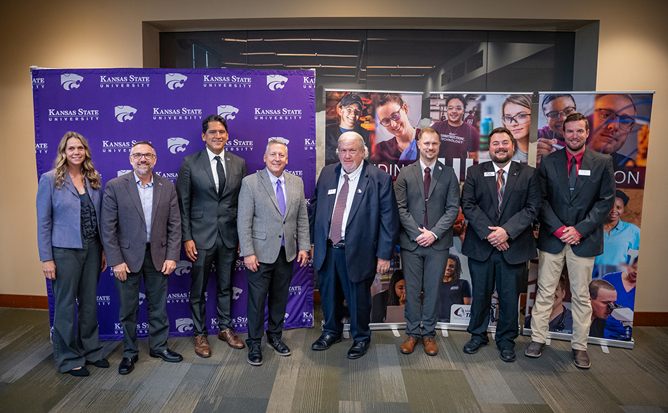 A group of K-State and Manhattan Tech administrators gather for a group photo in a residence hall.