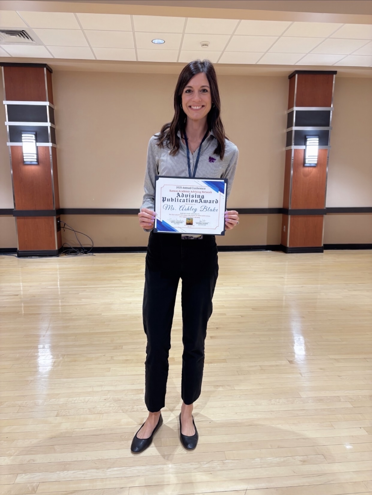 Ashley Blake holds up a certificate and smiles for a portrait. 