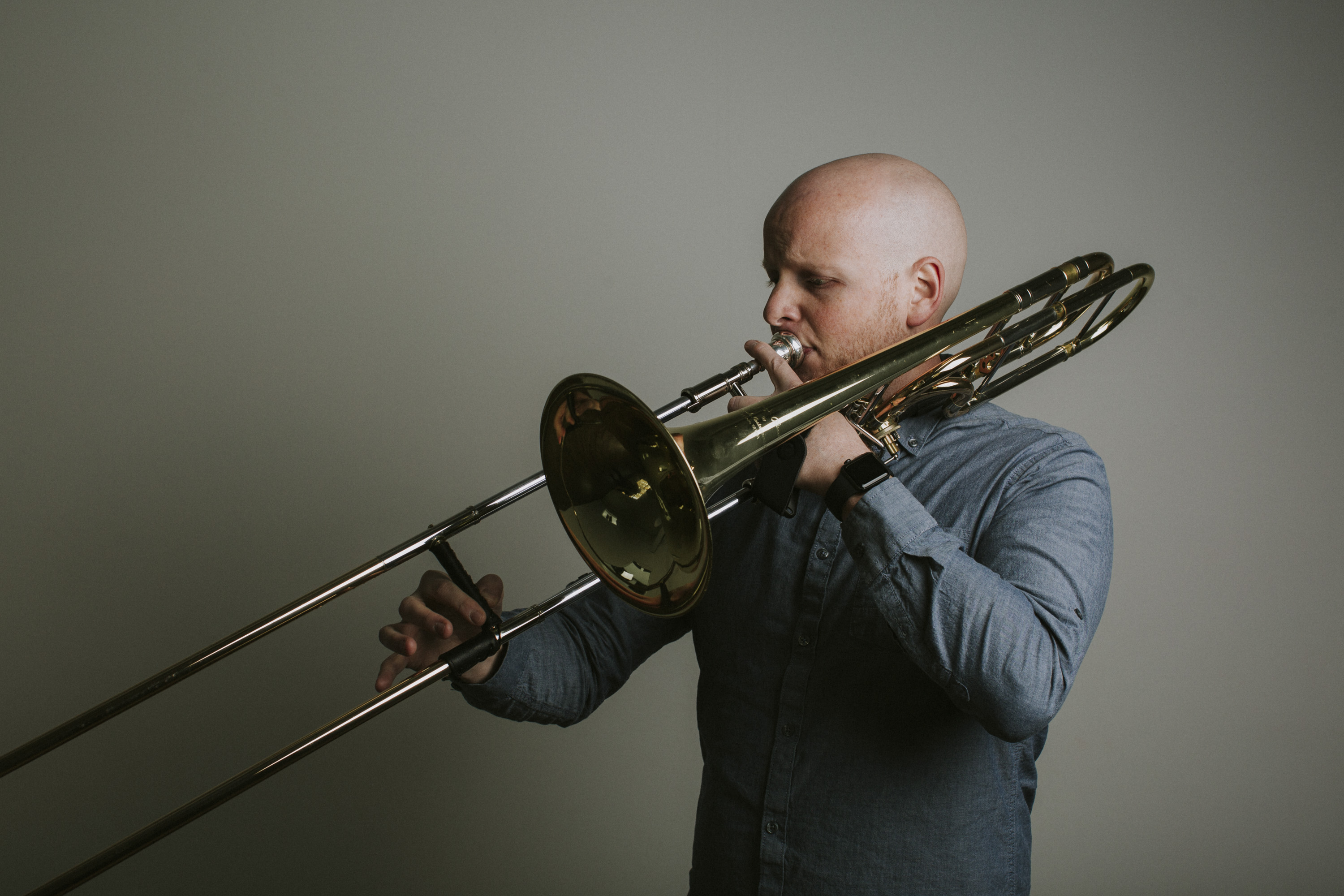 A man looks to the left and plays the trombone.