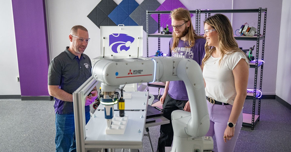 Two students listen as a K-State Salina instructor explains the robotic arm that is found on campus today.