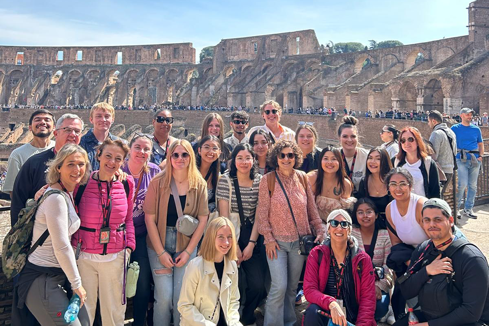 A group of college students gathers for a group photo inside the Colosseum in Rome, Italy. 