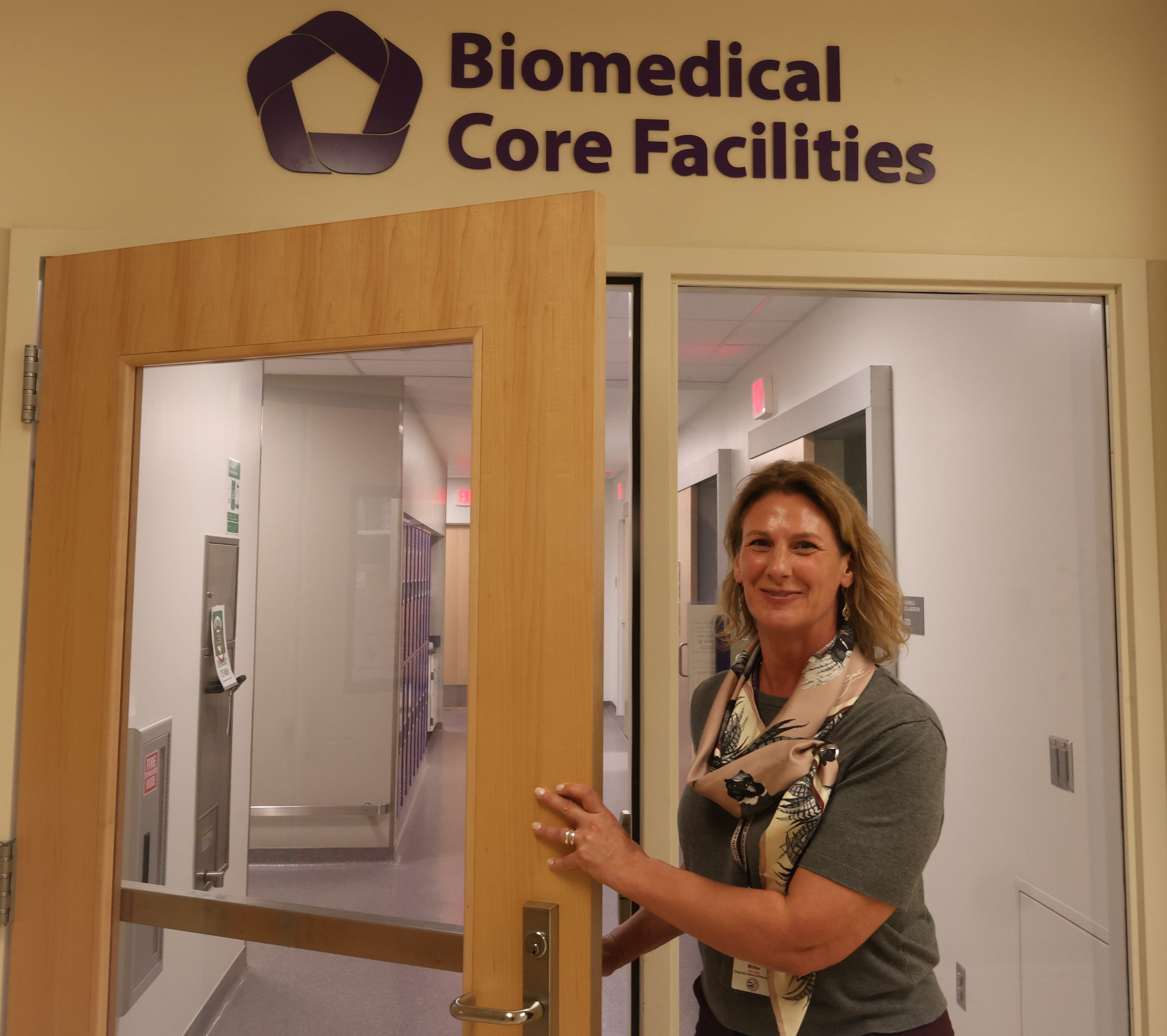 Laura Miller stands outside of a door in a hallway.