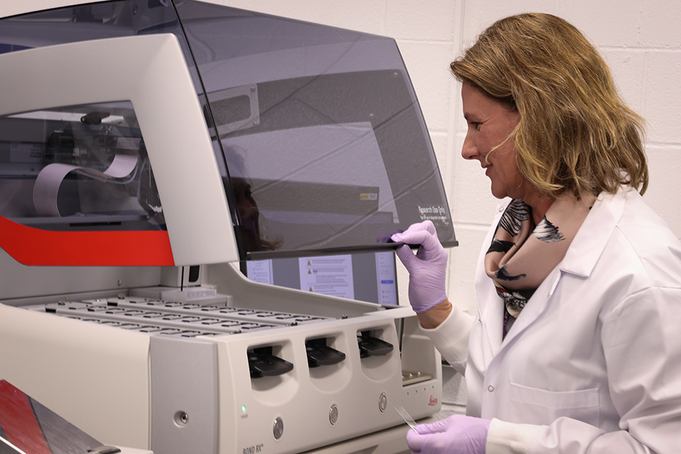 Laura Miller looks down at a machine in a lab.