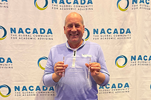 A man poses with a crystal award from NACADA.