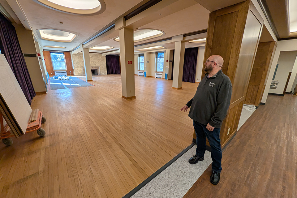 A college housing director stands and overlooks a newly renovated residence hall's lobby.