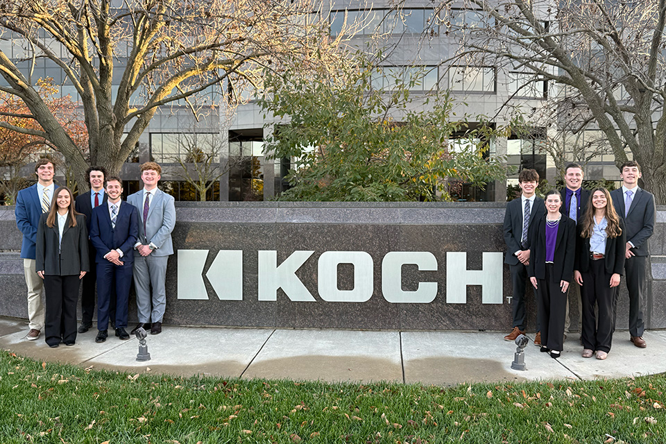Three men stand next to a large bonfire at night. 