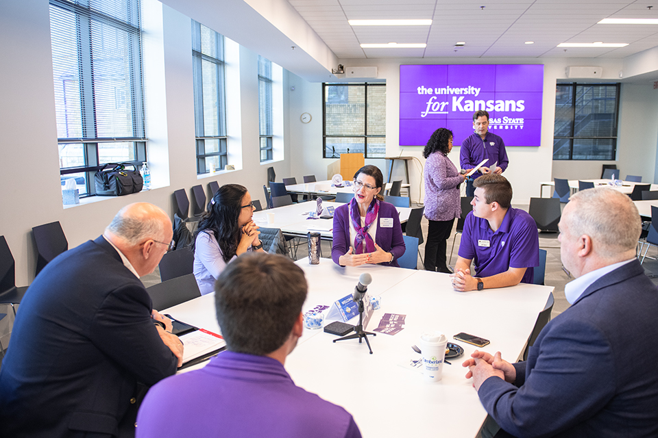 A group of community members sit at a table and discuss engagement in a conference room.