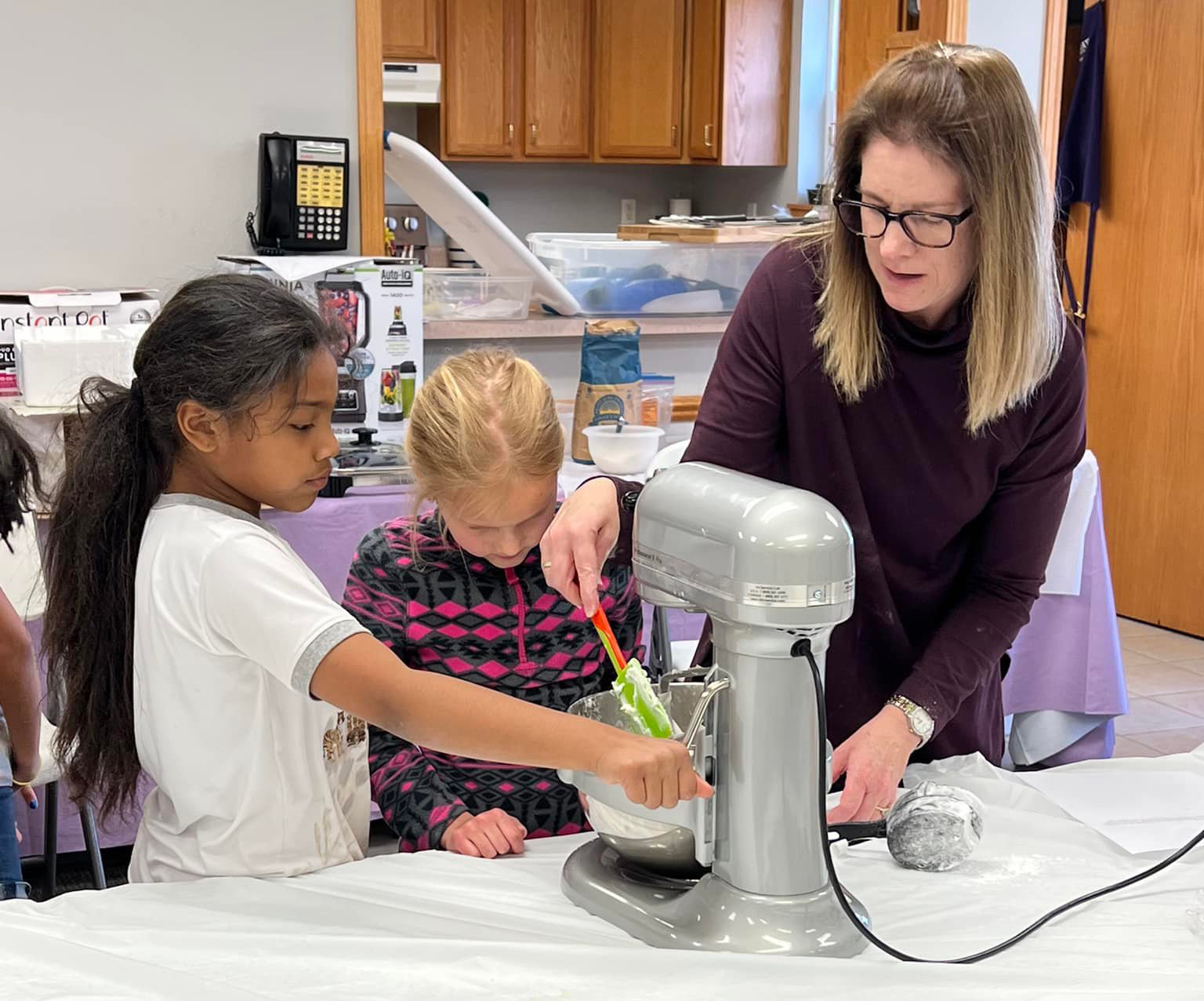 College professor Amanda Gaulke looks over a student's shoulder at a table.