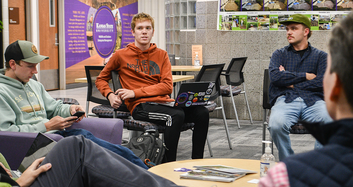 A group of college students sit in chairs in a cirlce engaging in a group discussion.