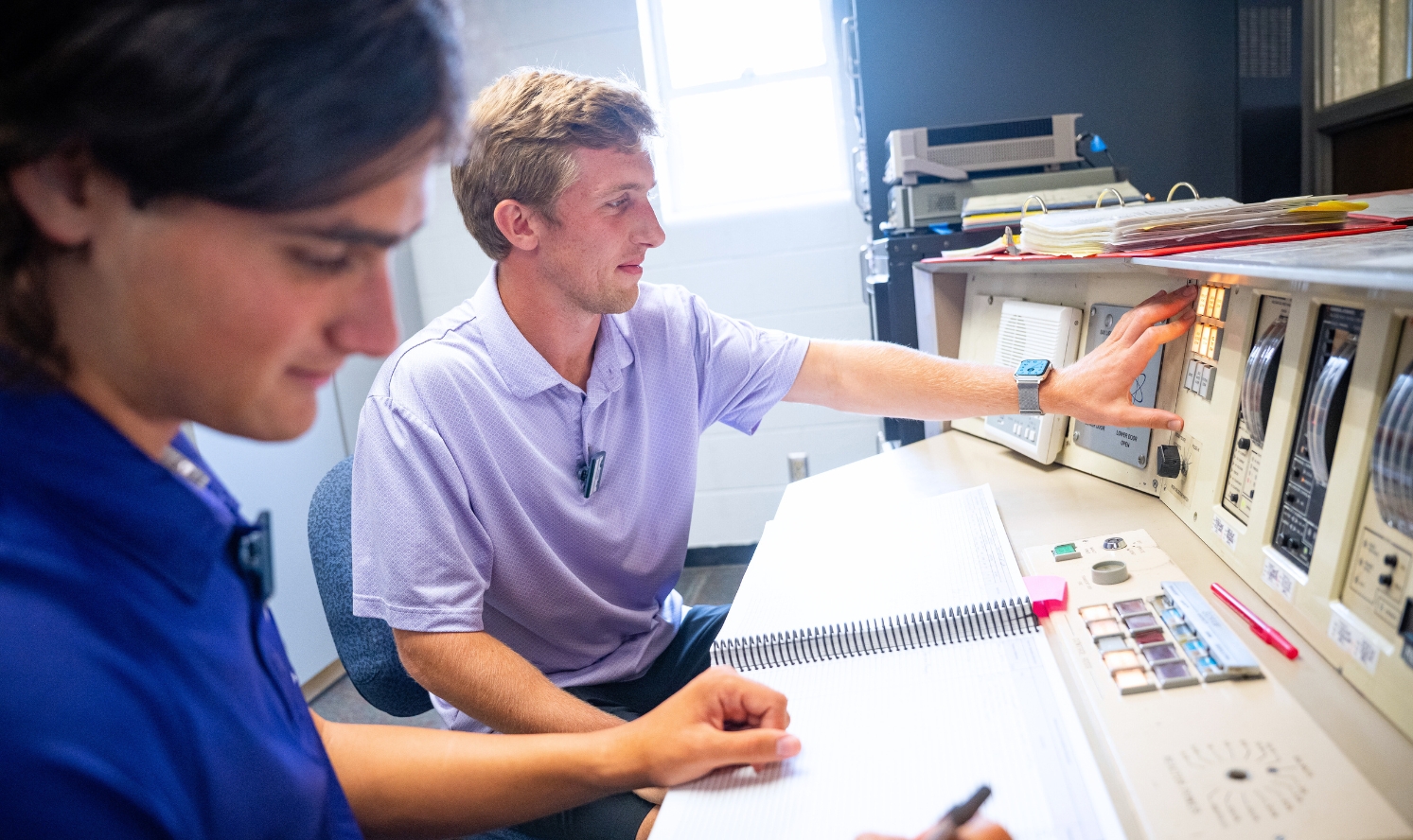 Danny Eckerberg, wearing a lavendar polo, works on the reactor's control panel.