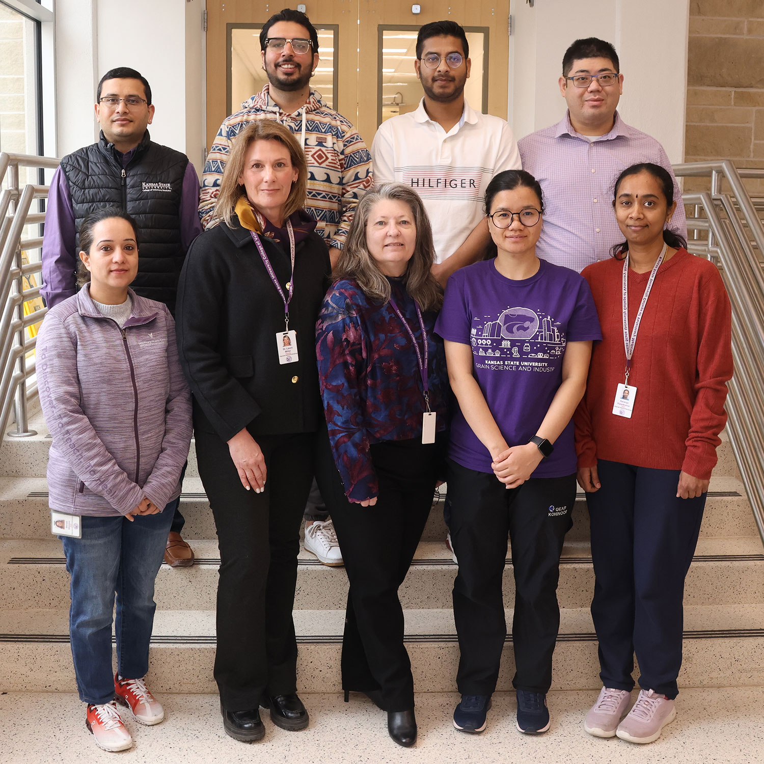 Nine people stand in two rows on a staircase, with four men on the top row and five women on the bottom row. The people pictured are researchers working to address avian influenza.