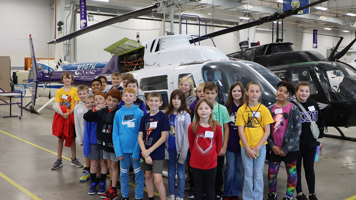 A group of about 20 elementary school kids stands in front of helicopters during one of K-State Salina's youth summer camps.