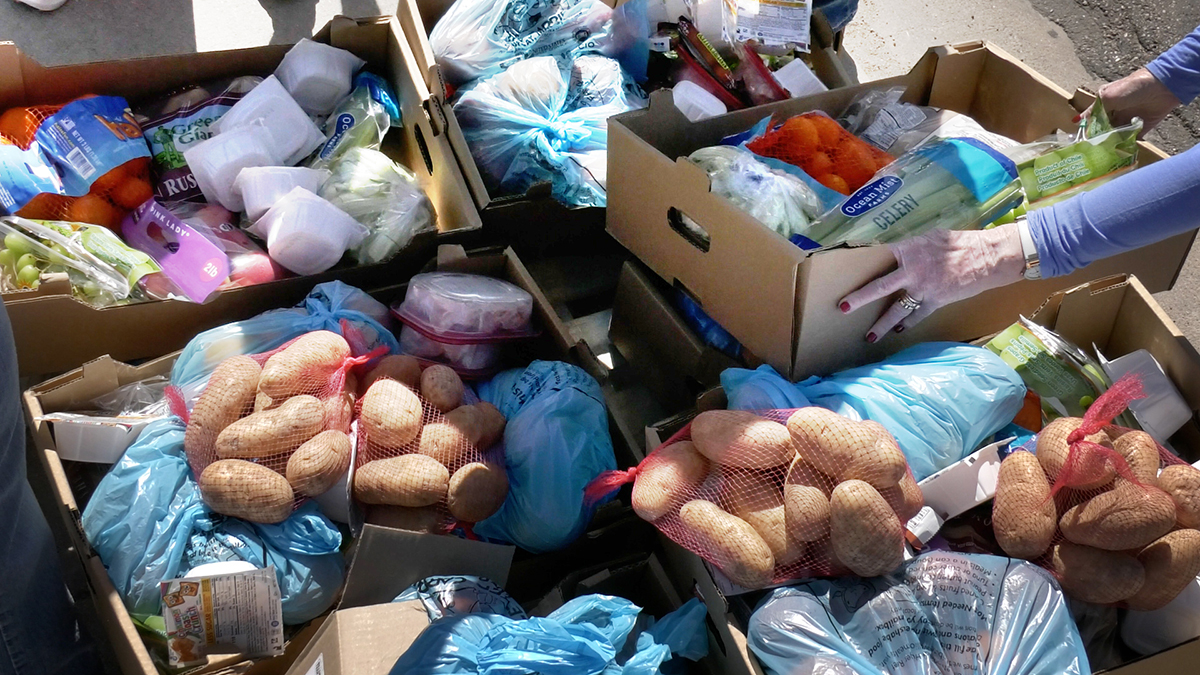 Boxes of various fruits, vegetables and other foods are pictured. Bags of potatoes, grapes and oranges pop with color.