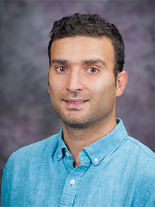 Hosein Baboly smiles for a portait in a blue button-up polo.
