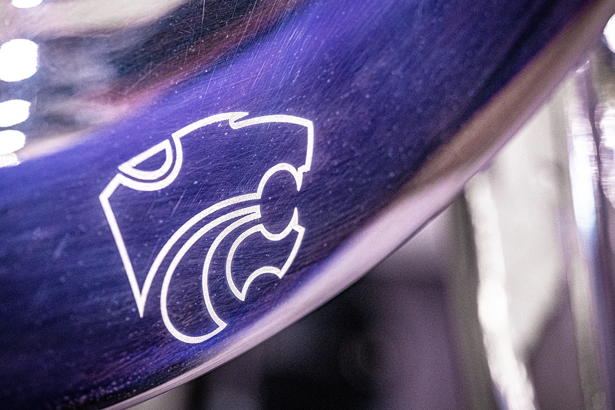 An engraving of a powercat logo gleams on the bell of a silver musical instrument.