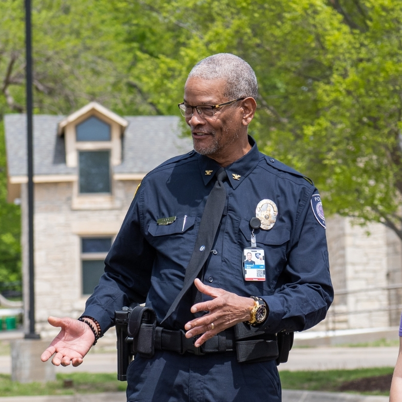 Ronnie Grice, wearing his K-State police uniform, engages with students outside of the K-State police station.
