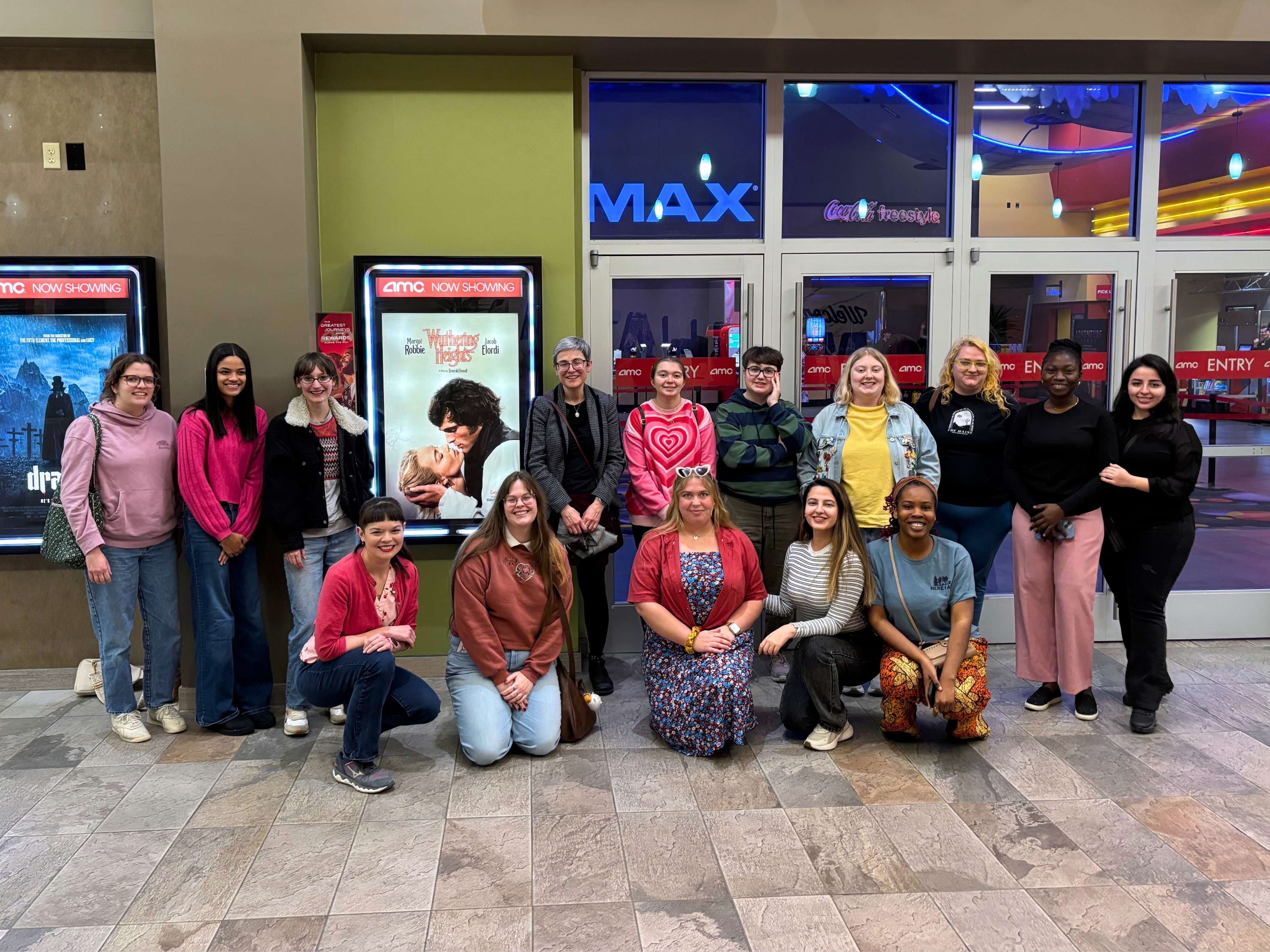 A group of students poses in front of AMC Theatre's Wuthering Heights movie poster.