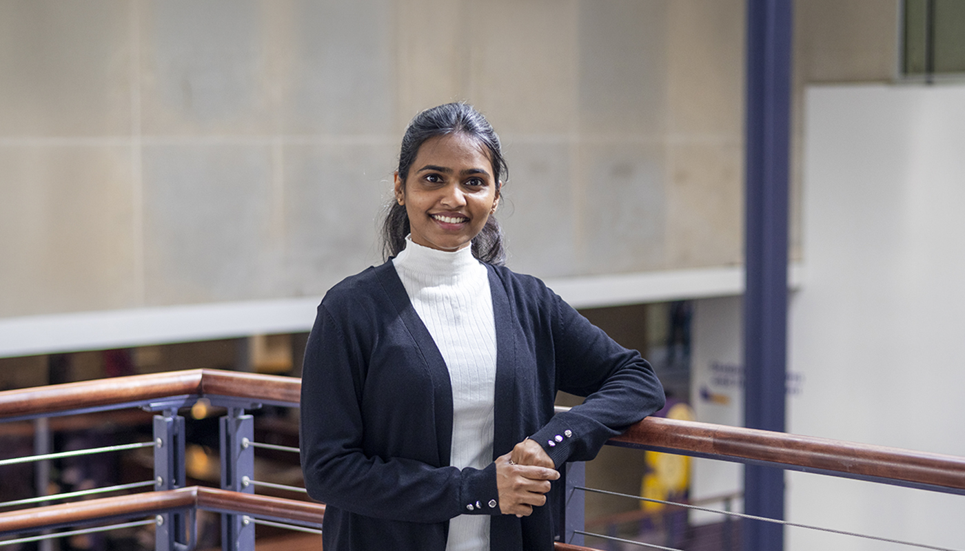 A female college student poses for a portrait in a student union courtyard.
