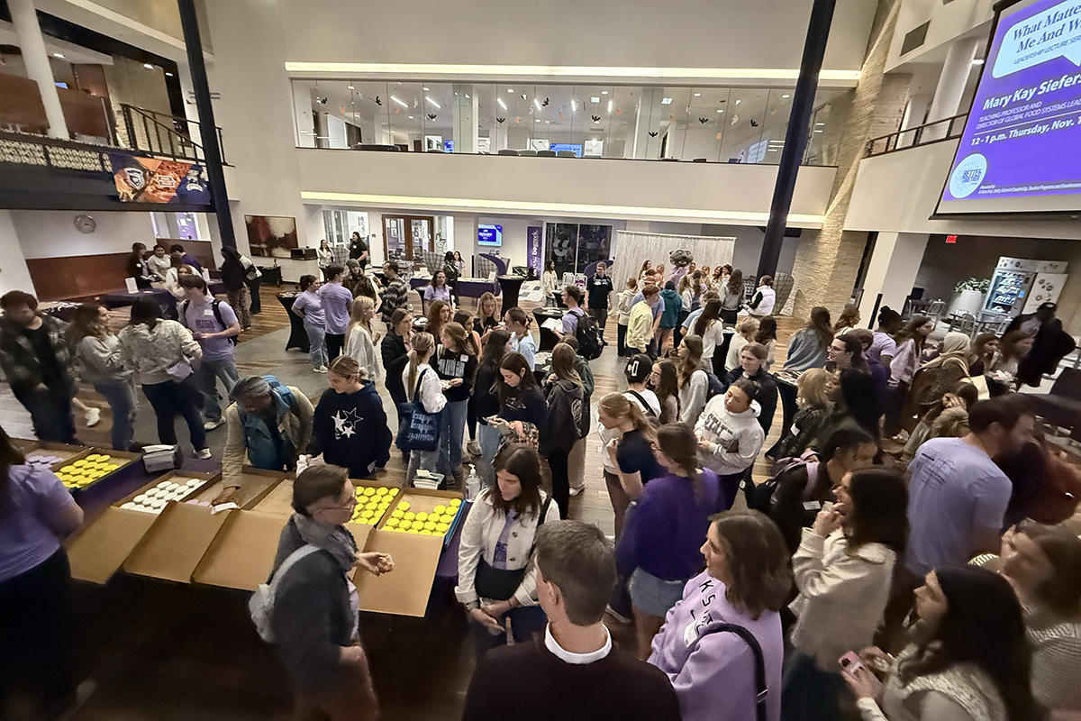 A crowd of first-year students visit booths in a student union courtyard.
