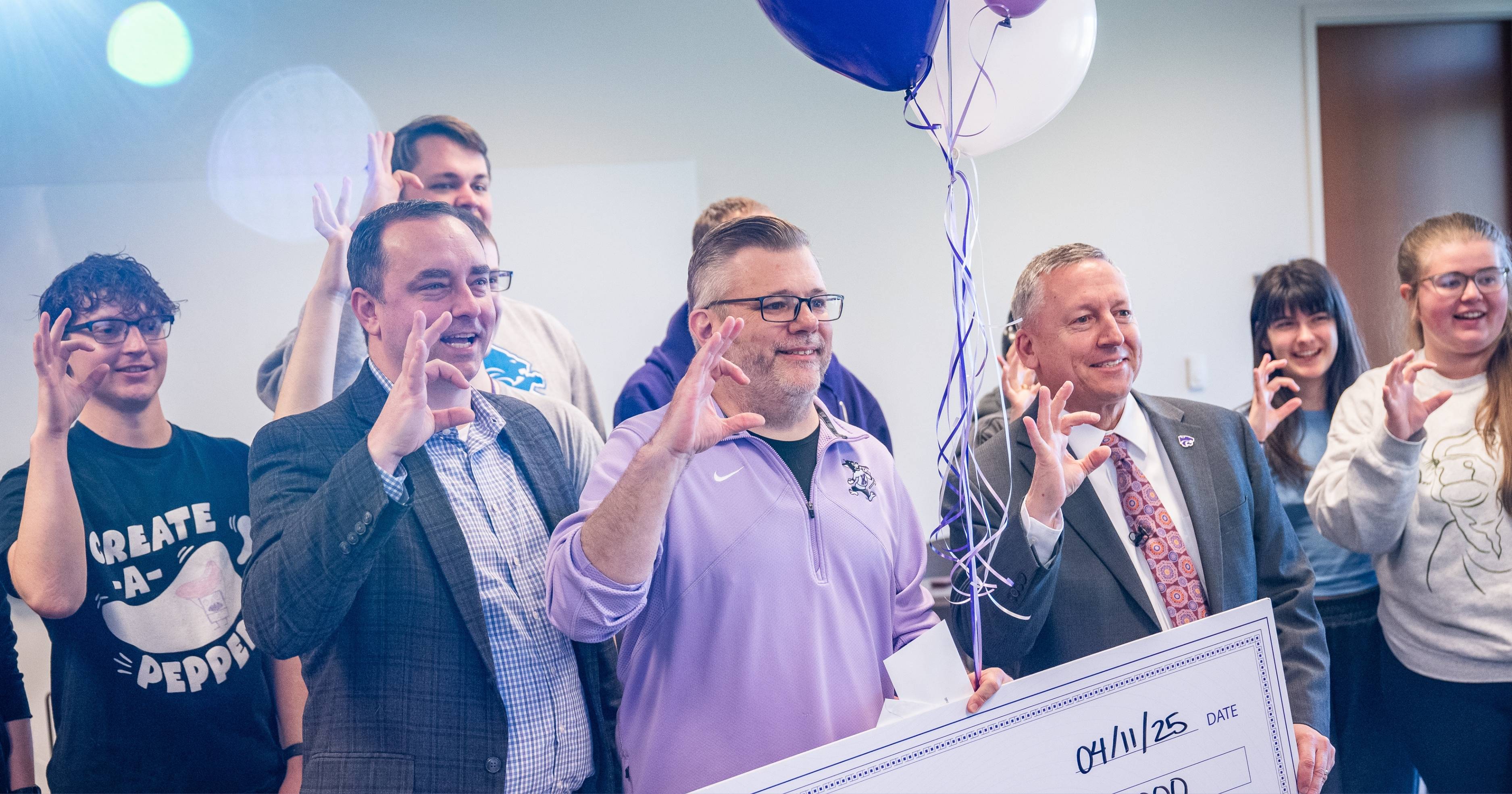 Jeremy Marshall shows a Powercat hand symbol as he receives an award.