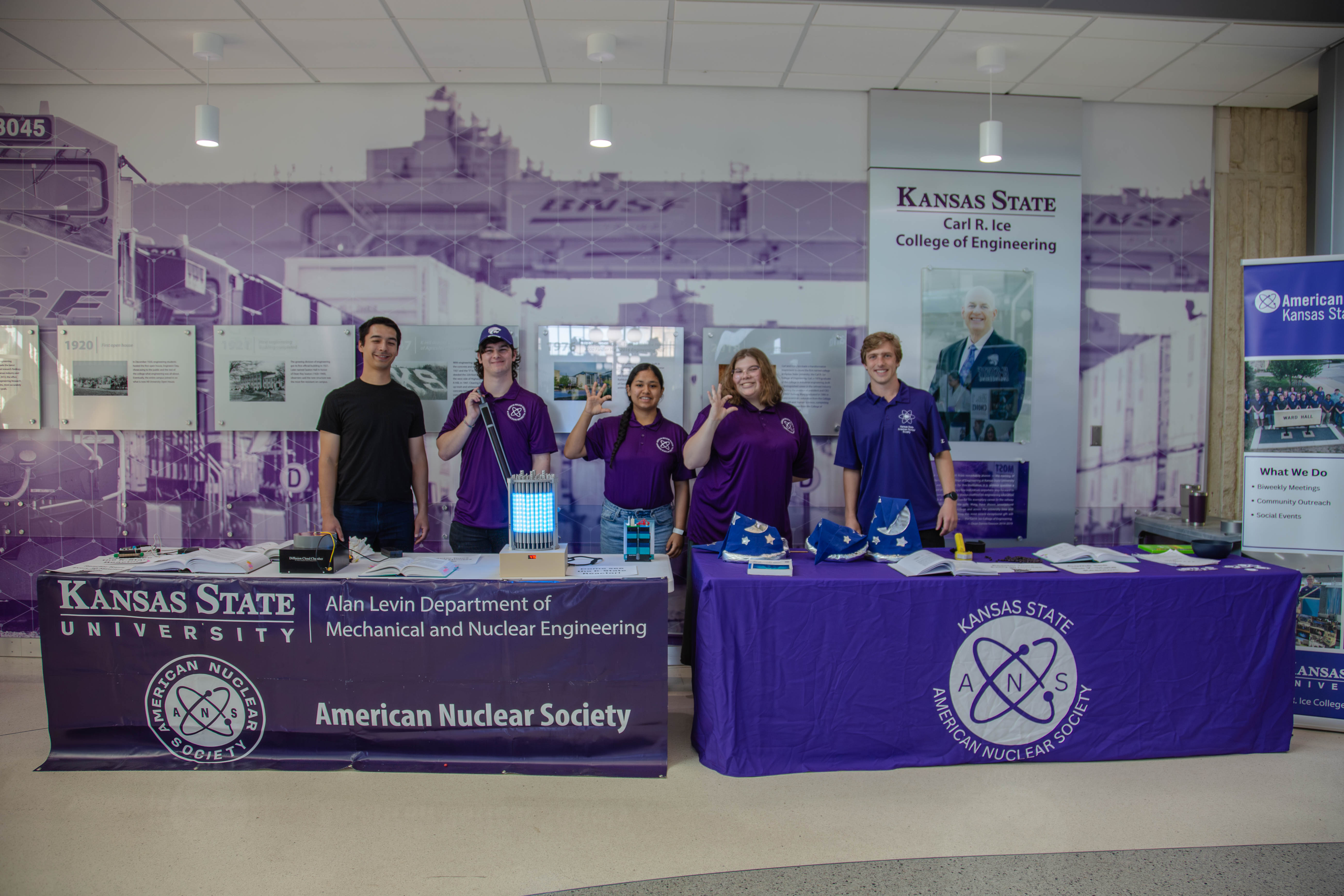 Kansas State University students staff an American Nuclear Society table inside the College of Engineering, displaying projects and engaging with visitors. 