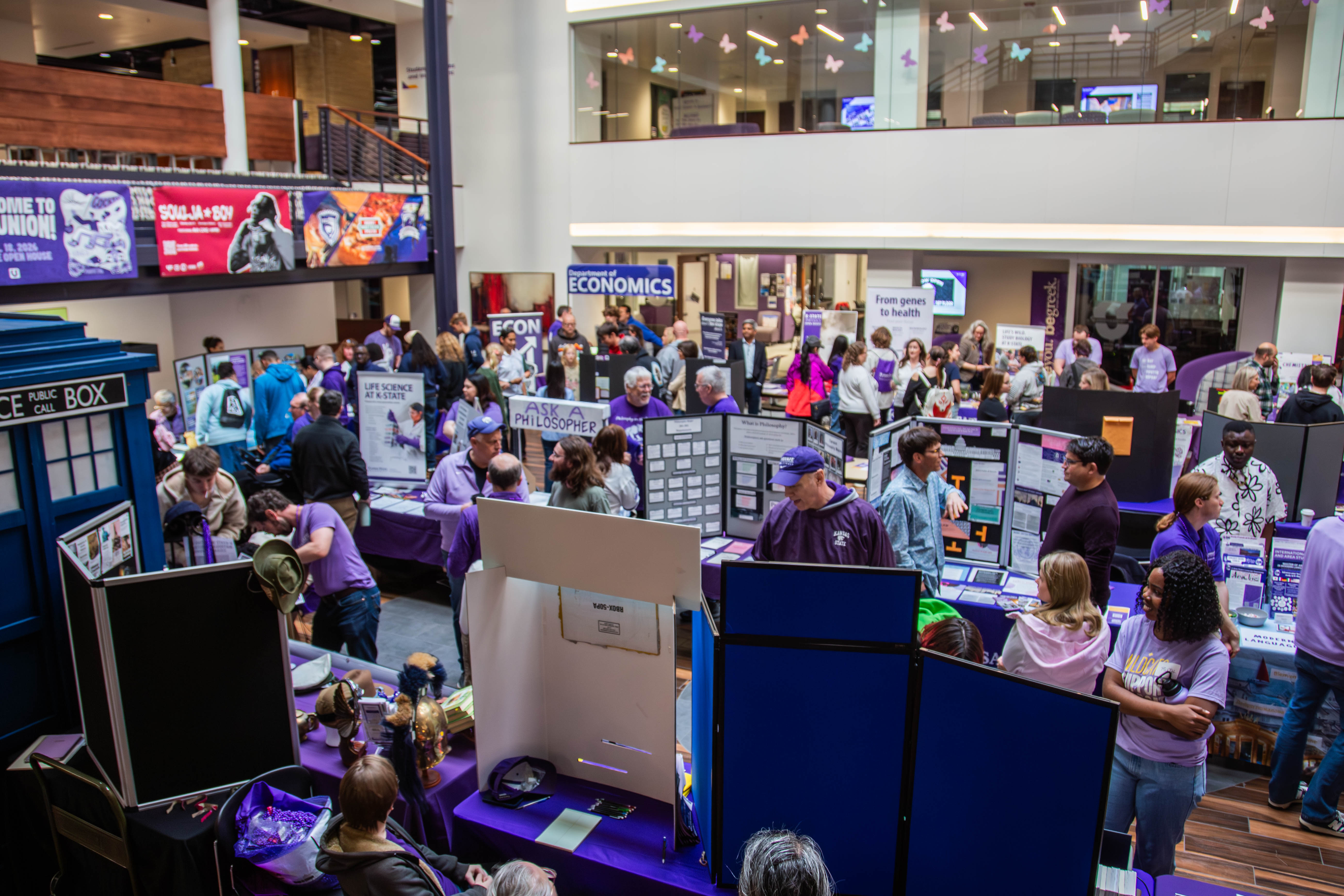 Aerial view of Kansas State University's Open House event in the Student Union with purple-decorated booths and interactive displays. 