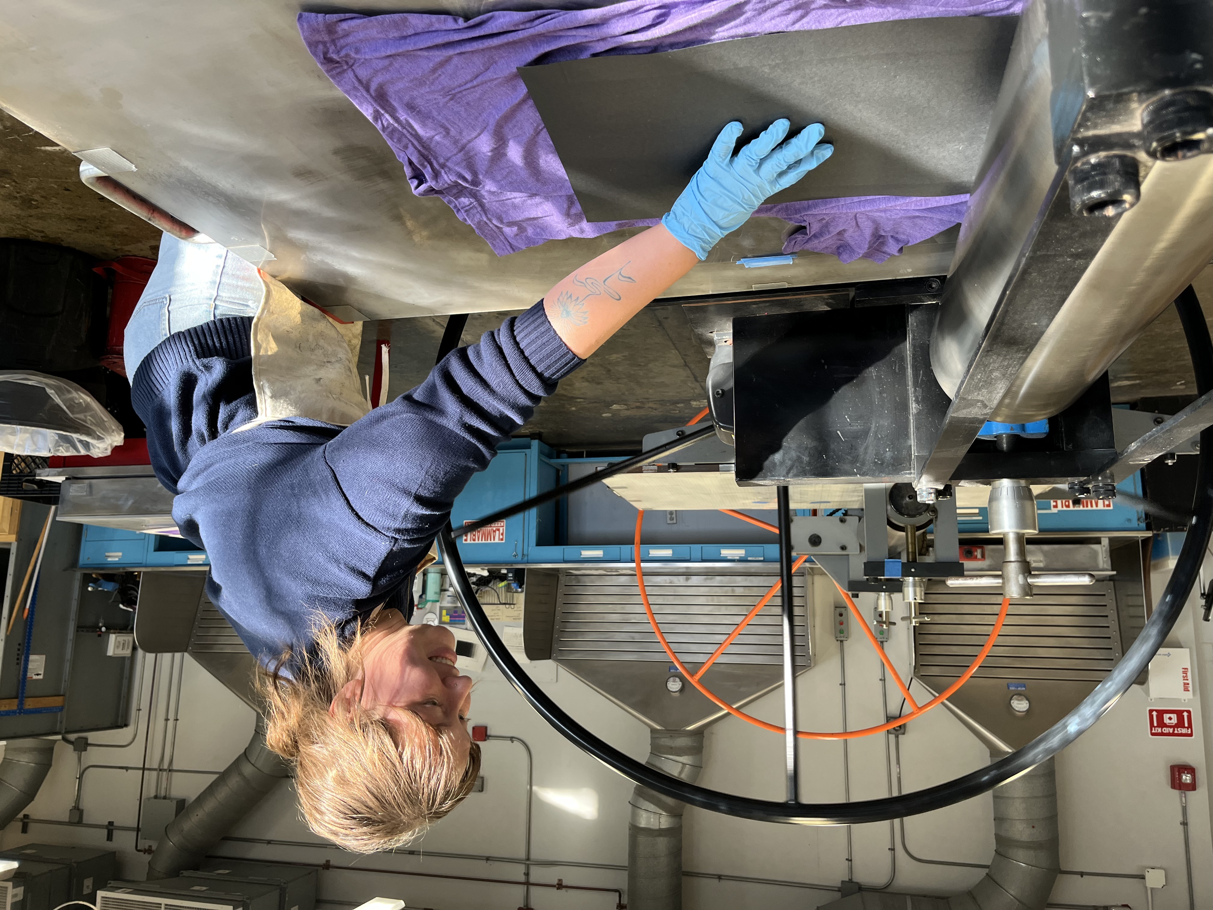 A young woman wearing a blue sweater prints a design on a shirt.