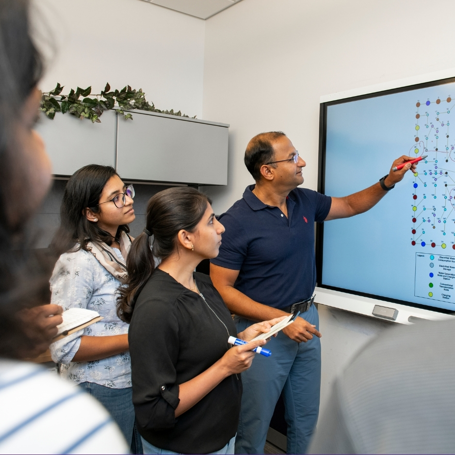 Bala Natarajan points at a screen while teaching