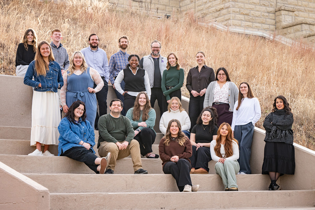 Adult members of a high school advising team pose for a group photo on a set of outdoor steps.  Cutline: Members of the KSCAC advising team. 