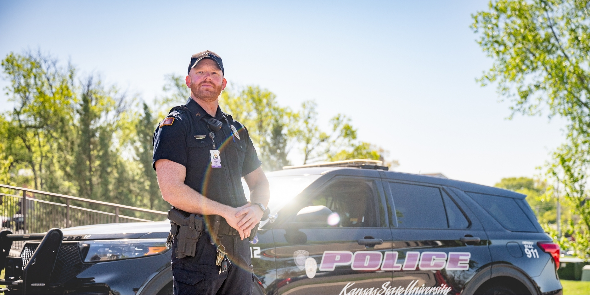 Kyle Casey stands in his uniform in front of a K-State police vehicle.