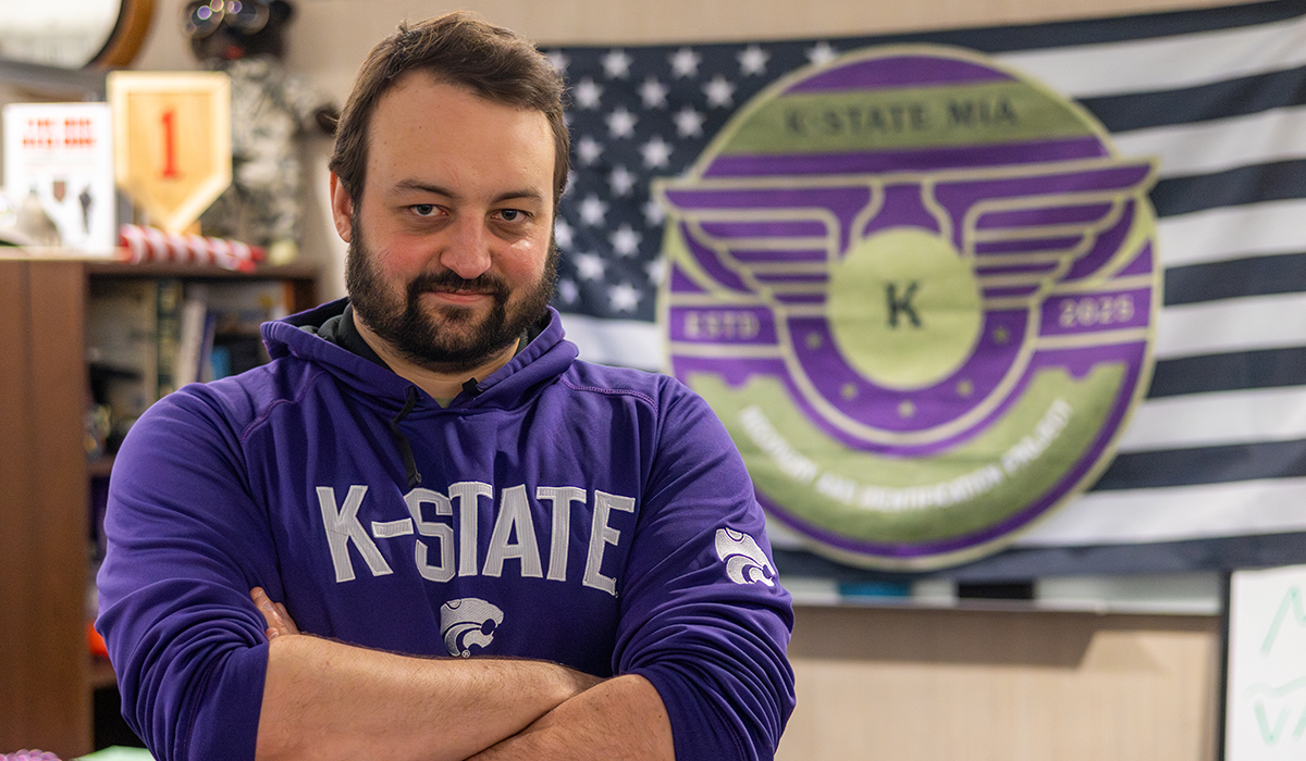 A doctoral student poses for a portrait in his cubicle in a military student support office.