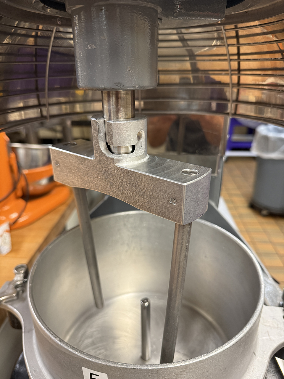: Dough mixing equipment is shown, emphasizing an attachment that goes on the mixer made of medal.