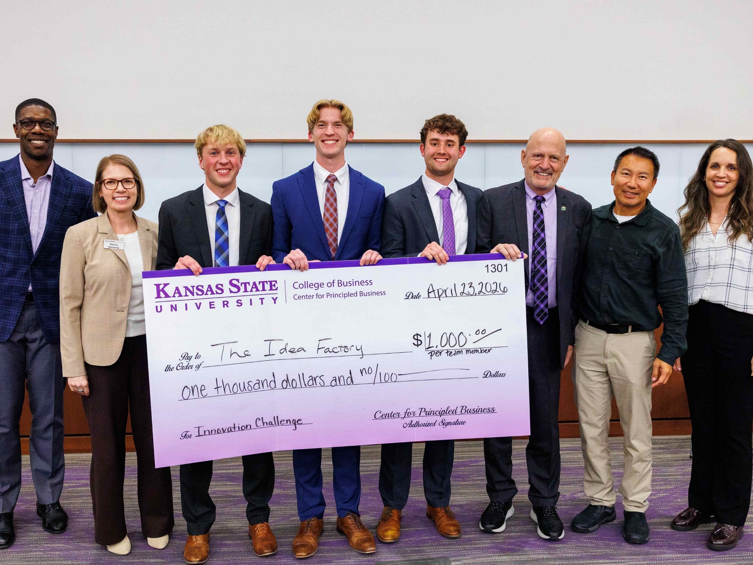 Students from the winning presentation, "The Idea Factory," pose with a $1,000 prize check and the judging committee