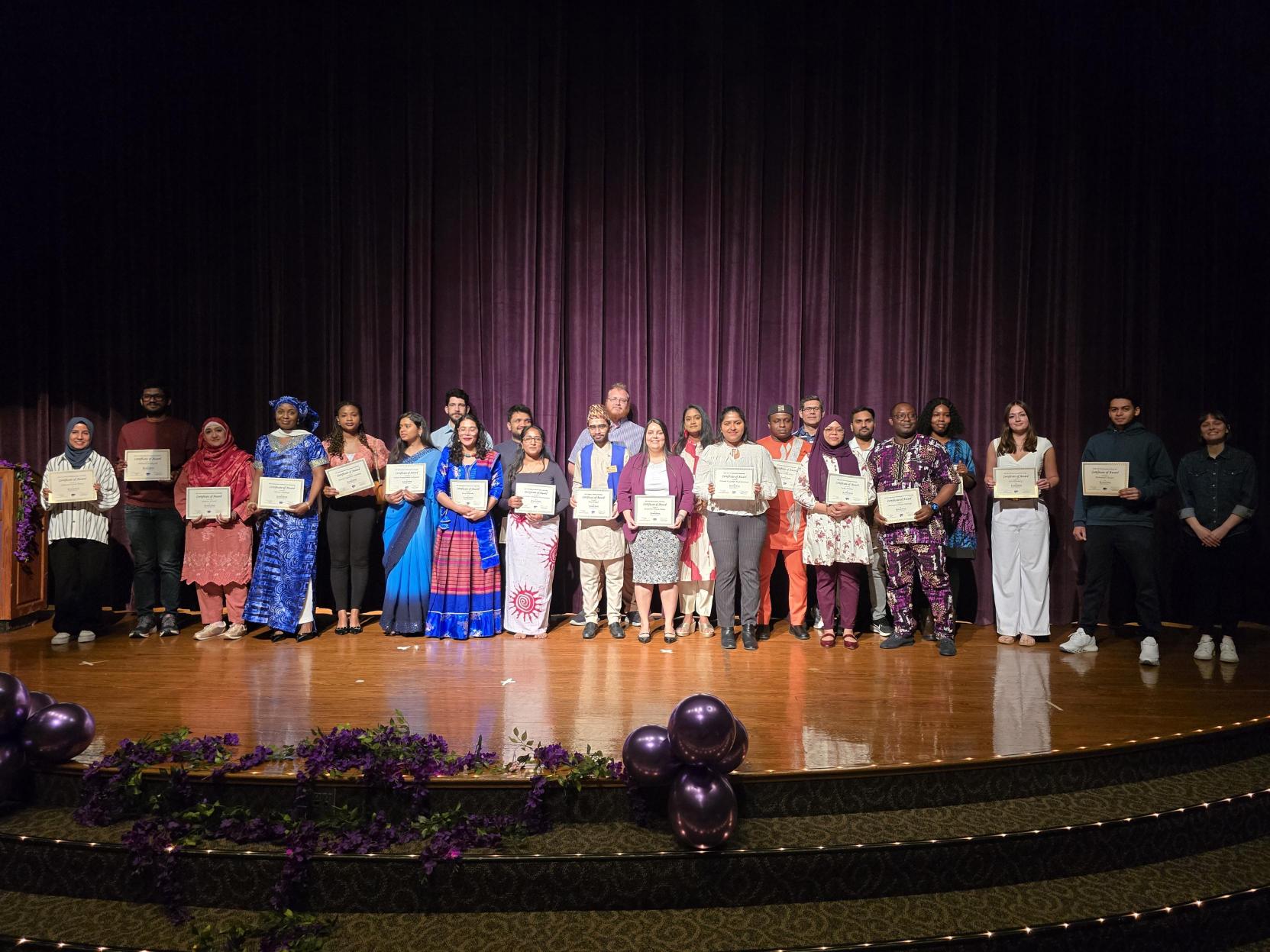 Student honorees from the ISSS and Alumni Association scholarship ceremony pose together for a photo on the stage in the K-State Union's Forum Hall.