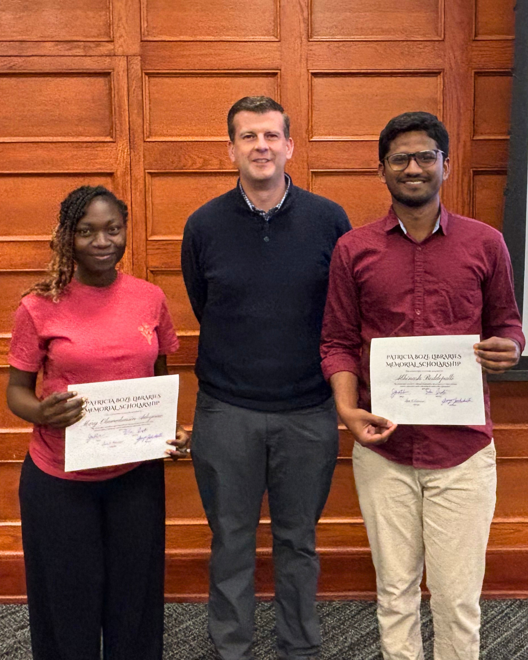 Mary Adeyemo (left) and Abhinash Boddepalli (right), K-State Libraries Student Ambassadors, stand with Dean James Wiser (middle) holding their Patricia Boze Libraries Memorial Scholarship certificates, presented by K-State Libraries.