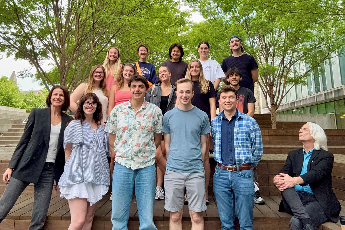 A group of college architecture students and their visiting professor pose for an outdoor group portrait on terraces.